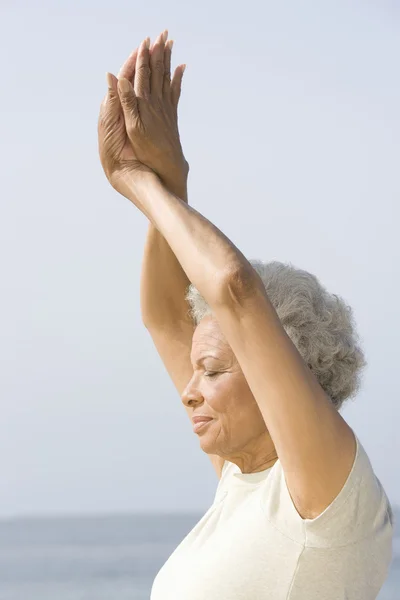 Donna anziana con gli occhi chiusi nella posa di yoga — Foto Stock