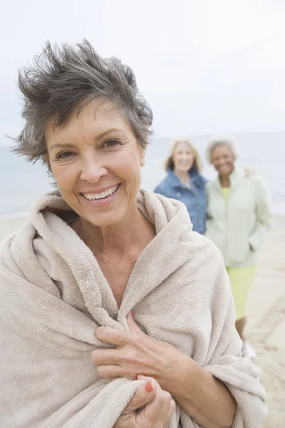 Зрелая женщина, завернутая в полотенце на пляже — стоковое фото