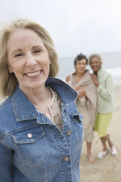 Mogen kvinna i denim jacka på stranden med sina vänner — Stockfoto