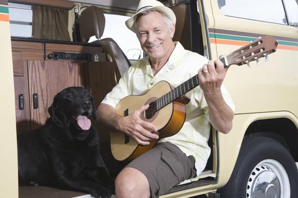 Homem sênior com seu cão tocando guitarra em Campervan — Fotografia de Stock