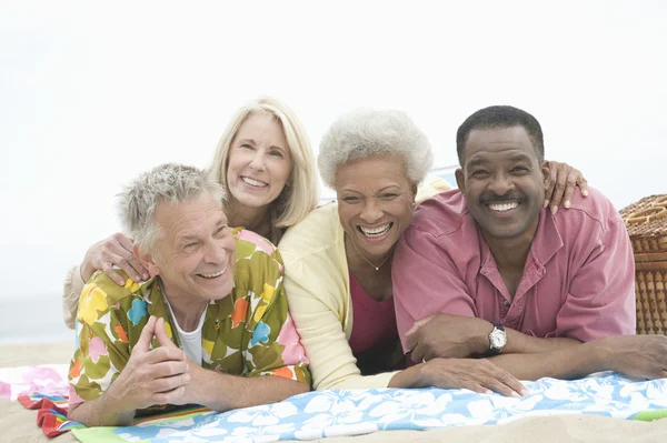 Multi-etnisch vrienden liggen op maag op strand — Stockfoto