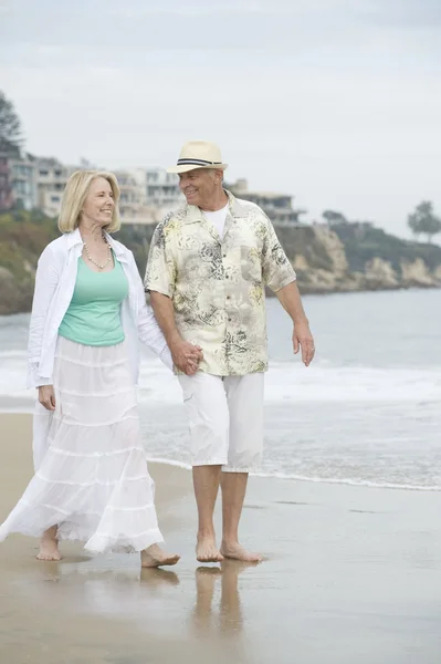 Старшая пара гуляет на пляже — стоковое фото
