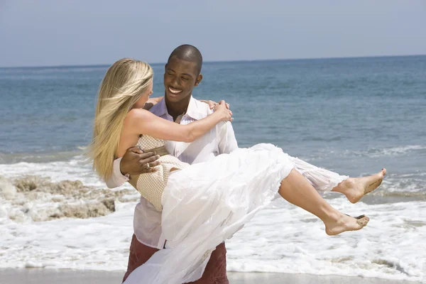 Homme portant femme à la plage — Photo