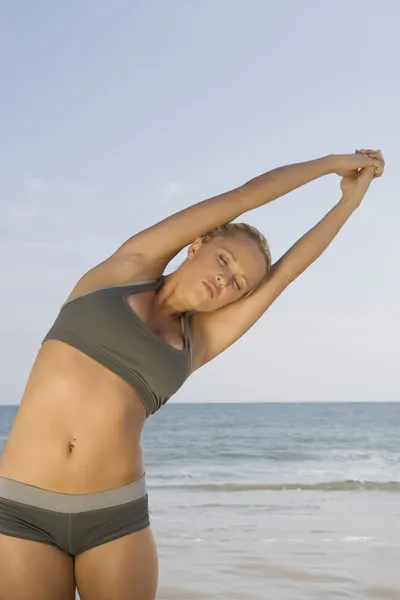 Mujer joven haciendo ejercicio en la playa — Foto de Stock