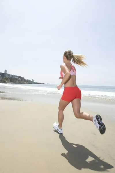 Vrouw joggen op strand — Stockfoto