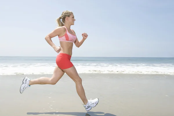 Frau joggt am Strand lizenzfreie Stockfotos