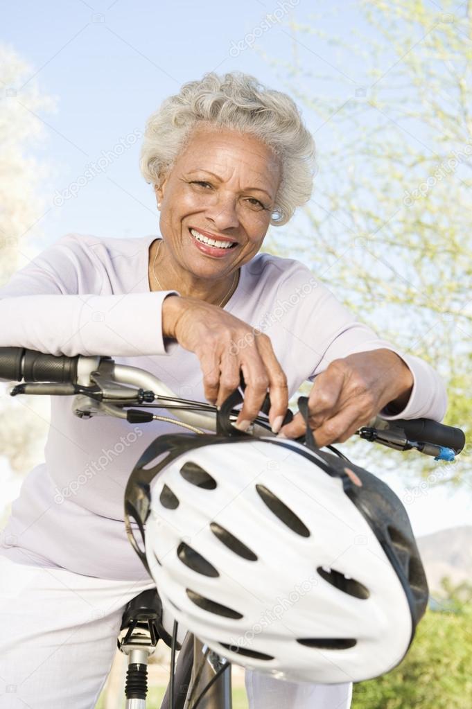 Senior Woman Leans On Handlebars Of Mountain Bike