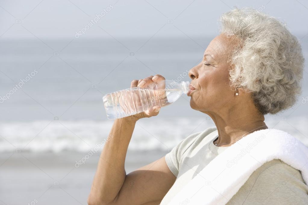 Senior Woman Drinking Water At Beach