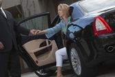 Chauffeur hilft Frau beim Aussteigen aus Auto