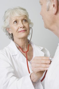 Doktor stetoskop kullanarak kontrol hastanın kalp atışı