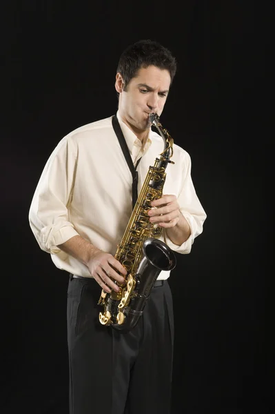 Homme jouant du saxophone sur fond noir — Photo