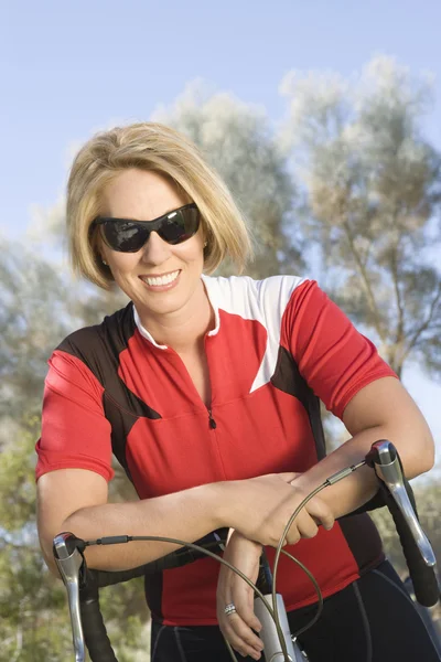 Ciclista feminina se apoiando na bicicleta — Fotografia de Stock