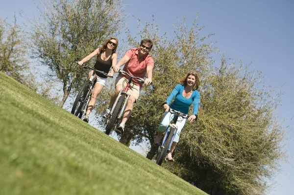 Mannen med två kvinnor cykling i park — Stockfoto