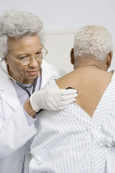 Läkare kontrollera Patient tillbaka med stetoskop — Stockfoto