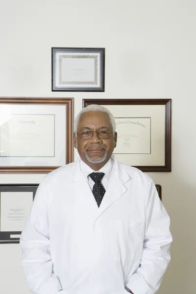 Doctor seguro con certificados enmarcados colgando en la pared — Foto de Stock