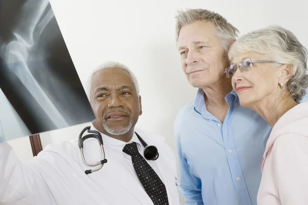 Senior male doctor with  patients and x-ray — Stock Photo, Image