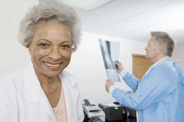 Femmina medico con collega esame radiografia in background — Foto Stock