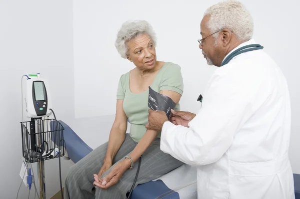 Врач измеряет кровяное давление пациента в клинике — стоковое фото