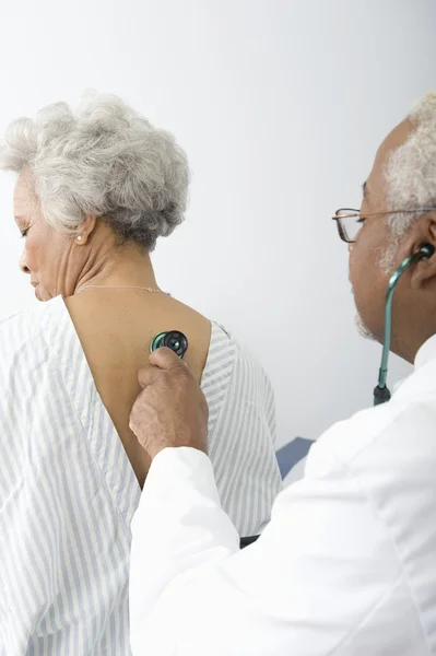 Médico Verificando as costas do paciente usando um estetoscópio — Fotografia de Stock