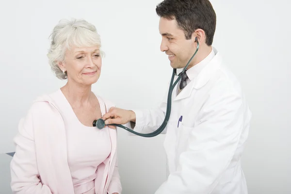 Médico revisando el latido del corazón del paciente usando estetoscopio —  Fotos de Stock