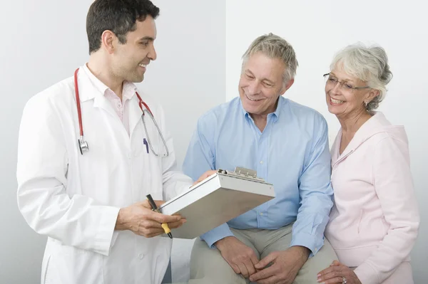 Medico Mostrando i rapporti ad una coppia anziana — Foto Stock