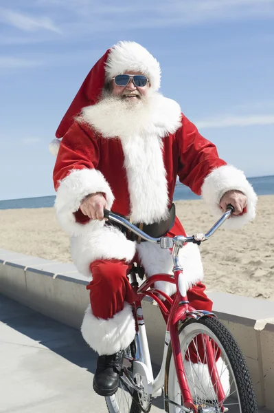 Père Noël faisant du vélo à la plage — Photo