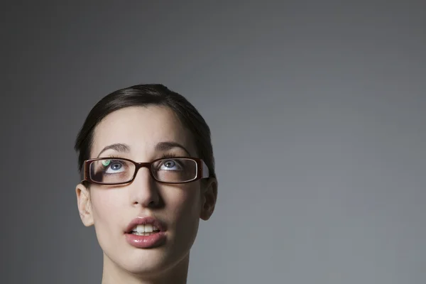 Joven mujer usando gafas mirando hacia arriba — Foto de Stock