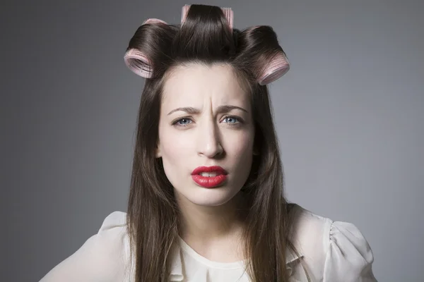 Jonge vrouw met rollers en rode lippenstift boos — Stockfoto