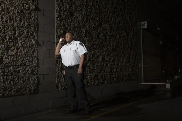Wachschutz patrouilliert nachts mit Taschenlampe — Stockfoto