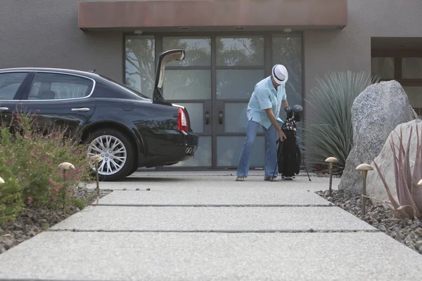 Mann hebt Golftasche in Kofferraum eines Autos — Stockfoto
