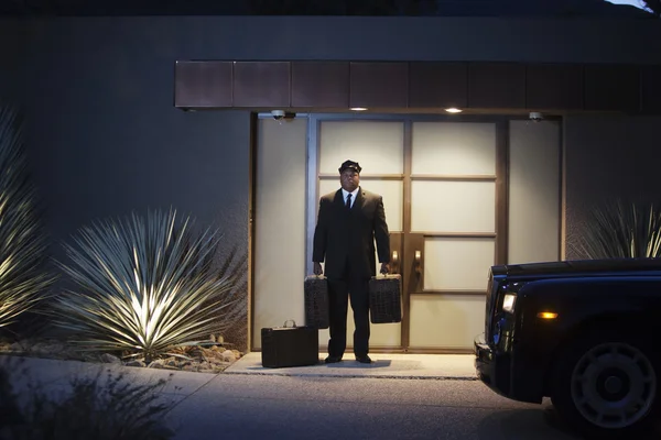 Chauffeur Stands At Lit Entrance Doorway With Luggage — Stock Photo, Image