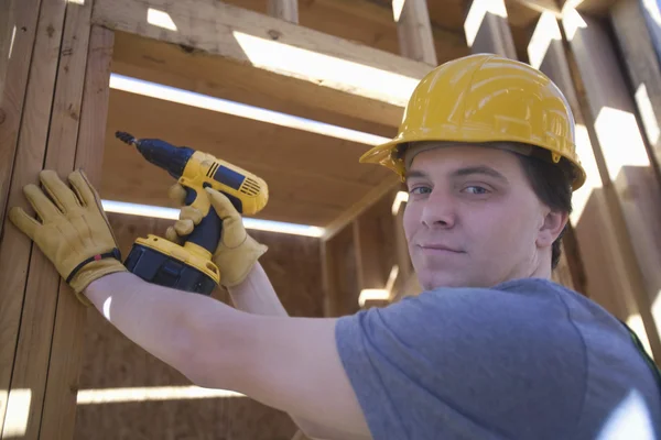 Uomo perforazione su un fascio di legno in loco — Foto Stock