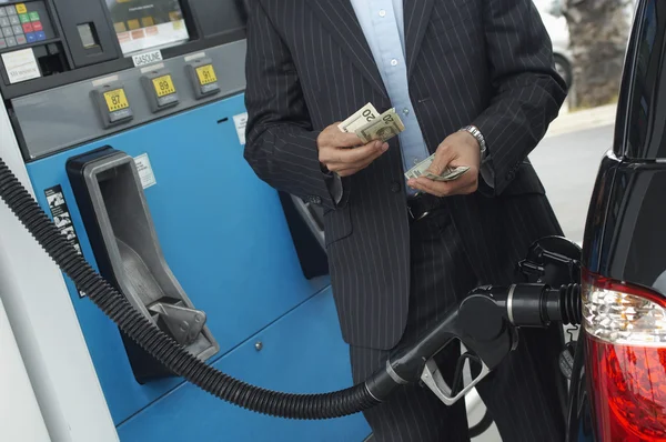 Geschäftsmann zählt Geld an Tankstelle — Stockfoto