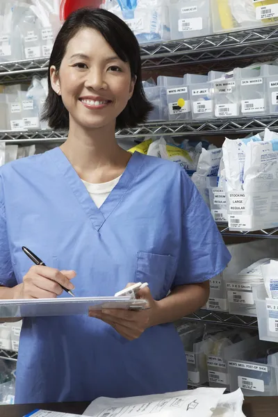 Farmacêutico feminino escrevendo na área de transferência — Fotografia de Stock