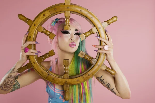 Young woman holding ship's wheel in front of her face — Stock Photo, Image