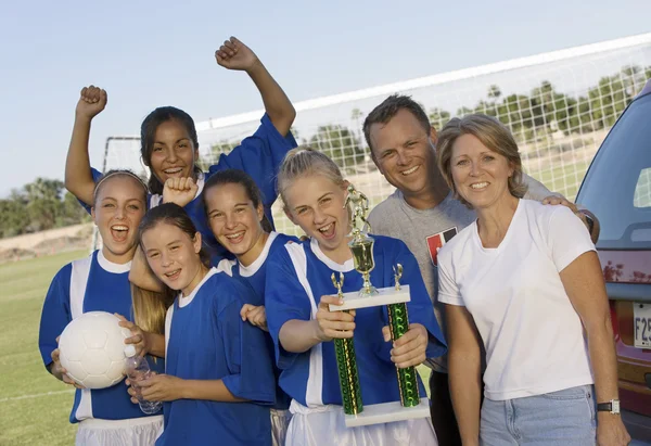 Jogadora de futebol feminino com amigos e pais segurando troféu — Fotografia de Stock