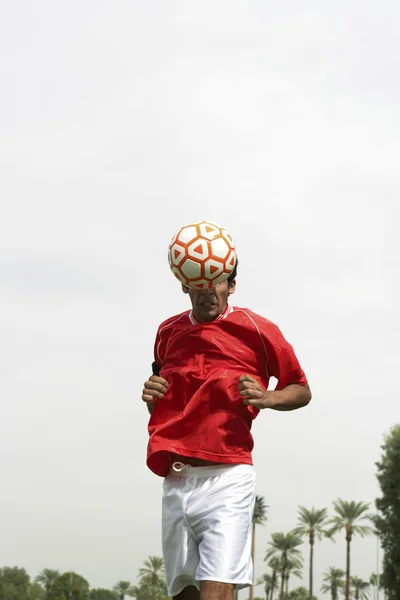 Футболист, возглавляющий мяч — стоковое фото