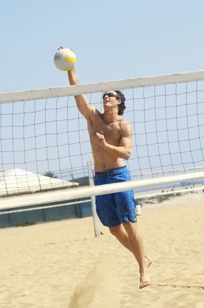Мужчина играет в волейбол на пляже — стоковое фото