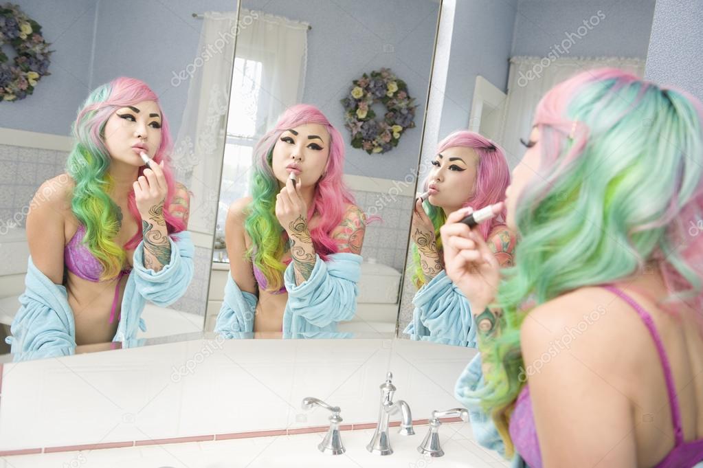Young woman applying lipstick on her lips with multiple mirror reflections