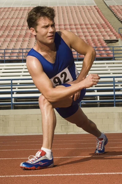 Runner stretching on a track — Stock Photo, Image