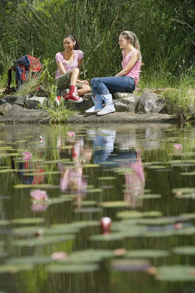 Caminhantes do sexo feminino descansando na lagoa — Fotografia de Stock