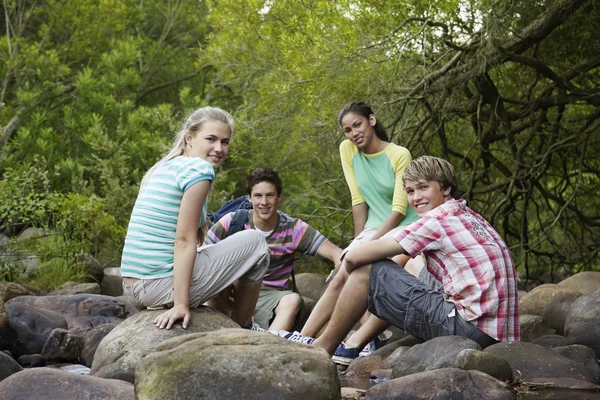 Cuatro amigos sentados en las piedras — Stockfoto