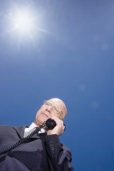 Uomo d'affari su chiamata contro il cielo — Foto Stock