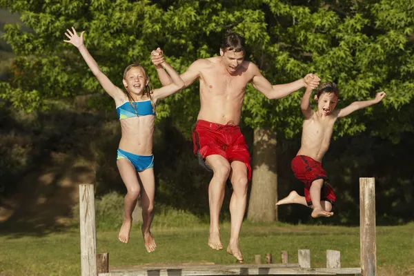 Familie springen in lake — Stockfoto