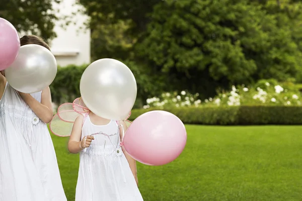Meninas segurando balões no jardim — Fotografia de Stock