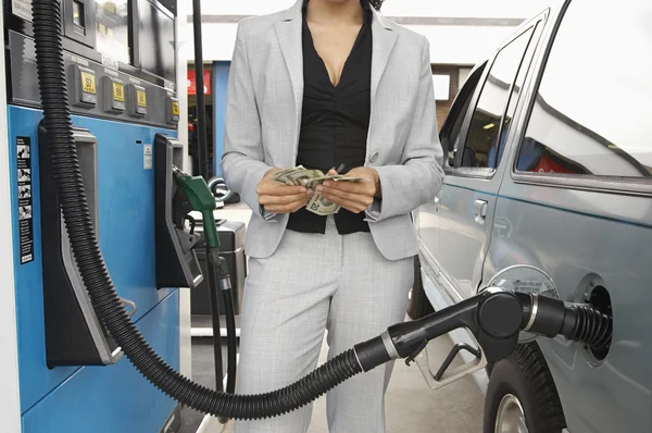 Mujer contando dinero en la gasolinera — Foto de Stock