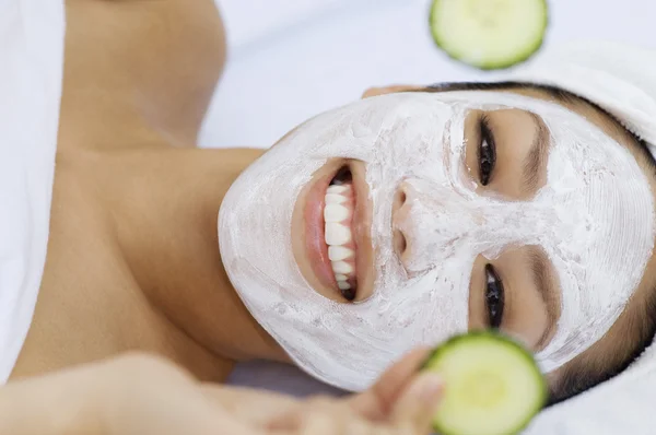 Mujer con máscara facial sosteniendo rodajas de pepino — Foto de Stock