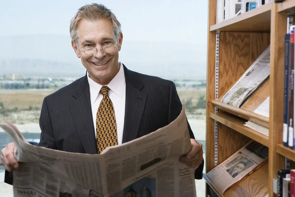 Affärsman läsa tidningen i biblioteket — Stockfoto