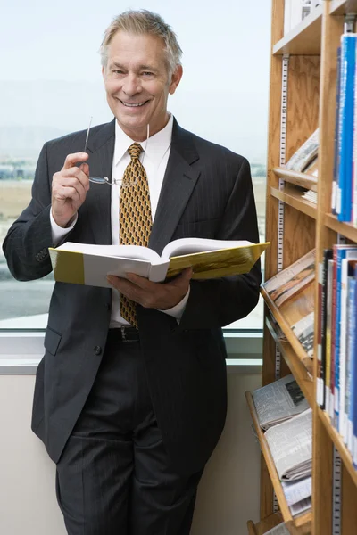 Χαμογελαστός άνθρωπος ανώτερα των επιχειρήσεων στη βιβλιοθήκη — Φωτογραφία Αρχείου