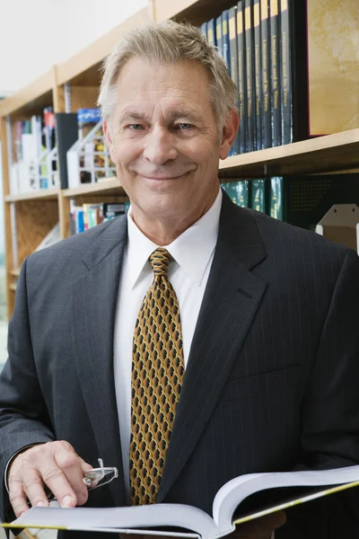 Businessman Standing In Library With Book — Stock Photo, Image